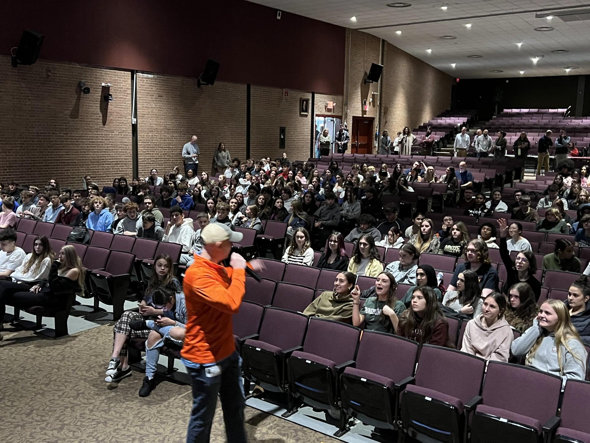 Mike Cardinal speaking with students in a high-school auditorium, heads fully in frame